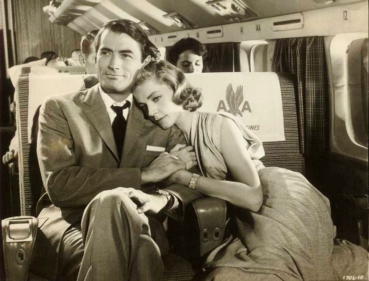 a man and woman are sitting on an airplane with their arms wrapped around each other