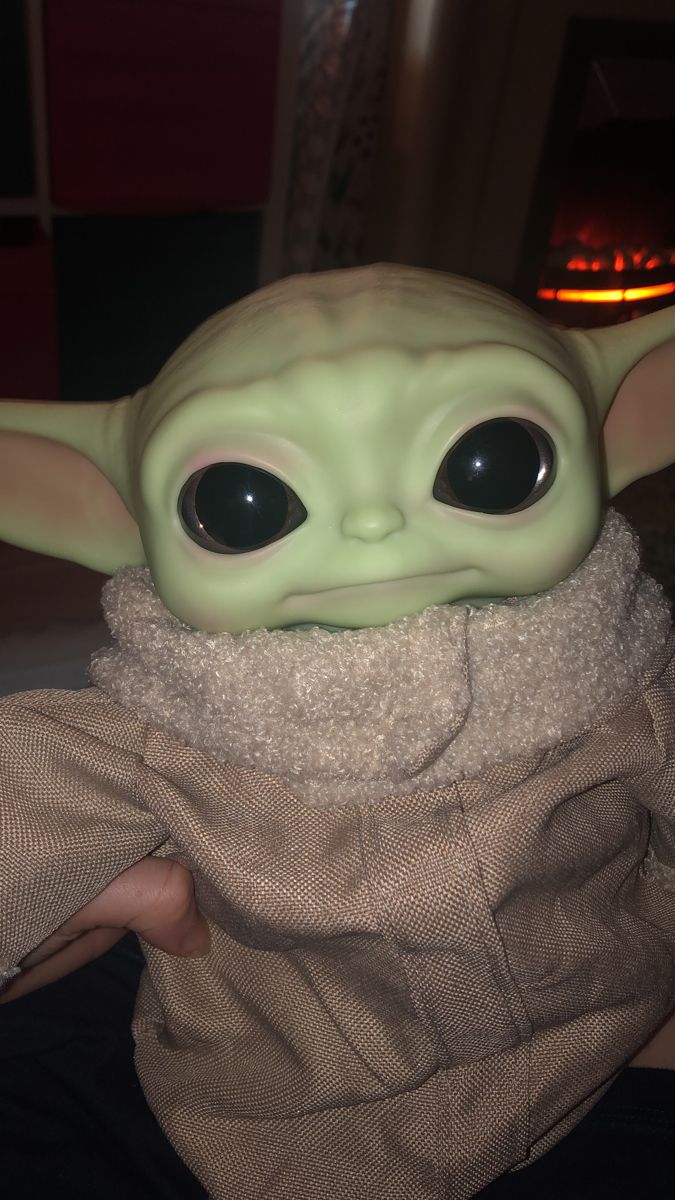 a baby yoda doll with big eyes and a scarf around it's neck