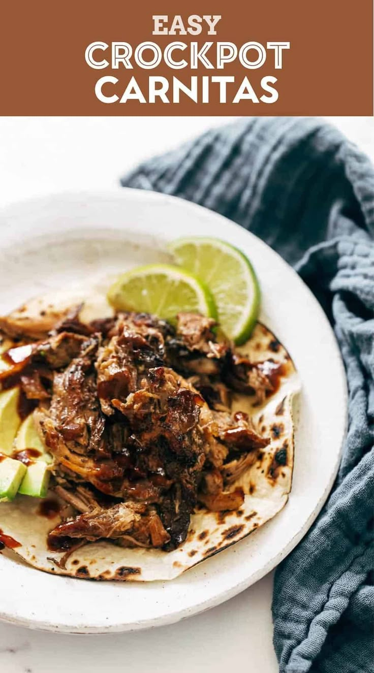 an easy crockpot carnitas recipe on a white plate with lime wedges