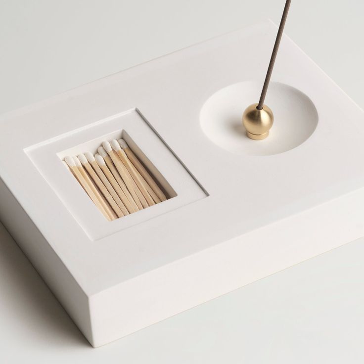 an object with sticks sticking out of it in a square frame on top of a table