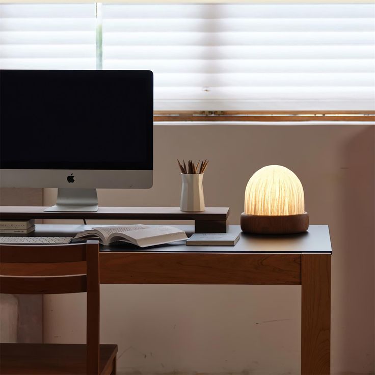 an apple computer sitting on top of a desk next to a book and pencils