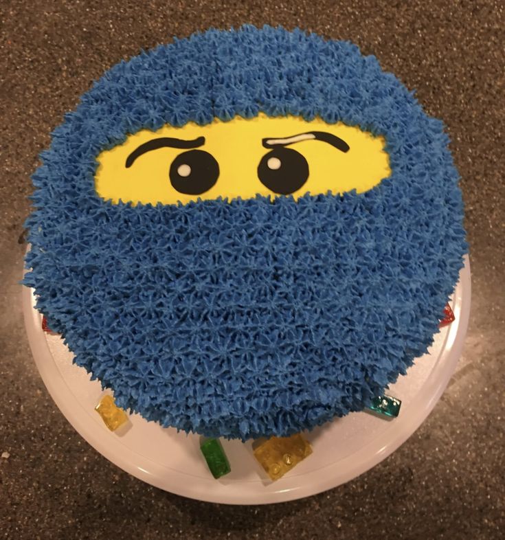 a cake with blue frosting and yellow eyes on it's face is sitting on a plate