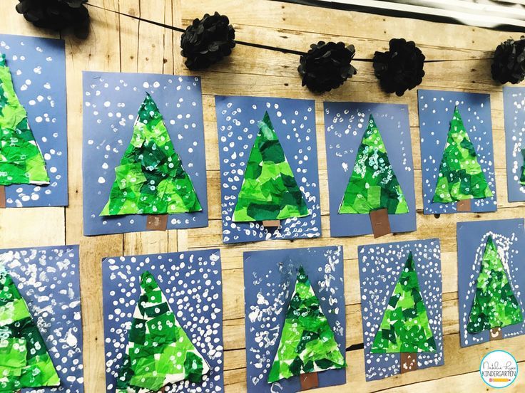 paper christmas trees are hanging on the wall in front of some black pineconis