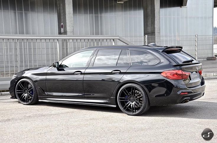 a black bmw car parked in front of a building with its trunk open and the back end