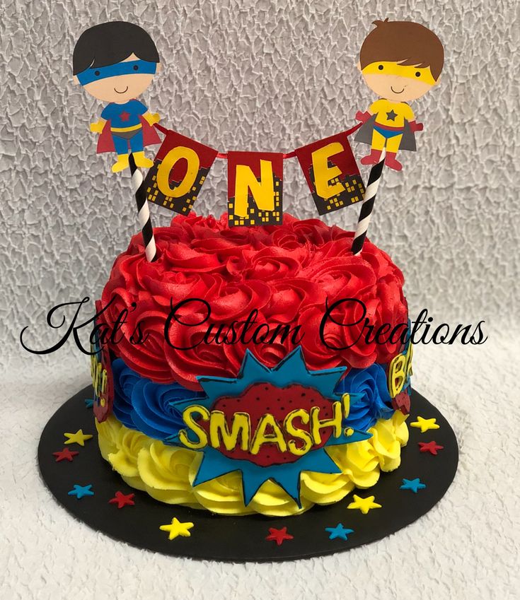 a birthday cake with two boys on top and the words smash spelled in red, blue, yellow and black