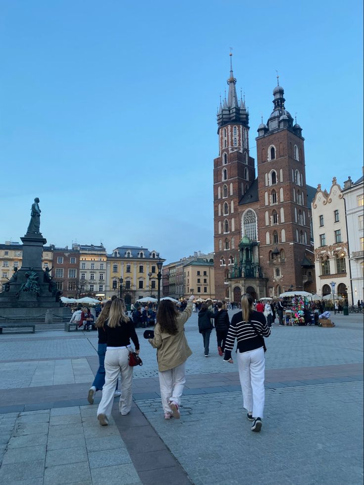 three women walking in front of a large building with towers on it's sides