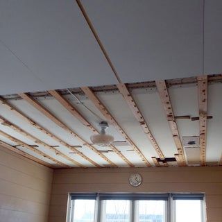 a room that is being remodeled with wood beams on the ceiling and windows in it