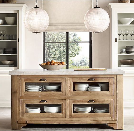 a kitchen with white cabinets and an island in front of the window, filled with dishes