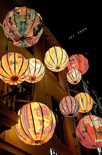 many colorful lanterns hanging from the side of a building