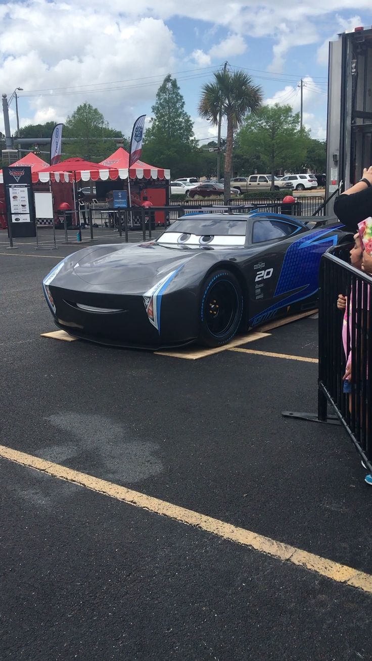 a woman and child standing next to a car in a parking lot with other cars