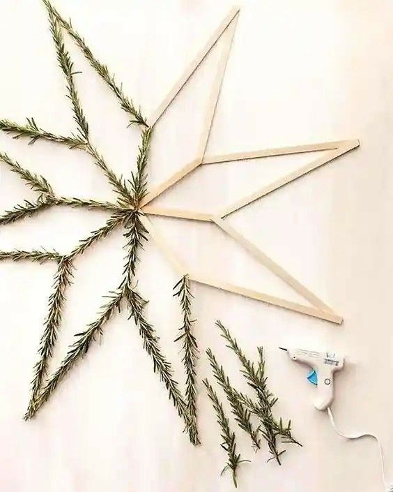 several branches are arranged in the shape of a star on a white surface with scissors and thread