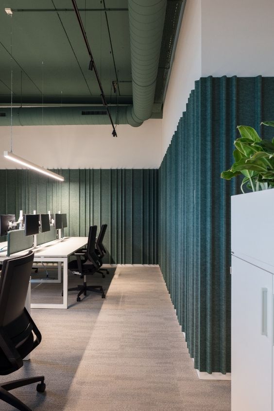 an empty office with desks and chairs in the center, along with green curtained walls