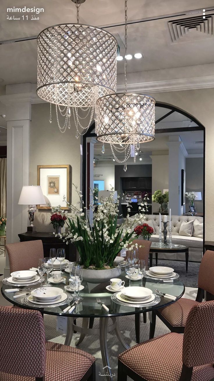 a dining room table set with place settings and flowers on the centerpiece, in front of a mirror