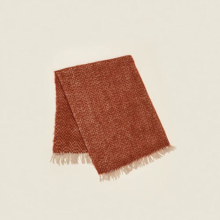 an orange and white scarf with fringes on the ends, laying flat against a white background