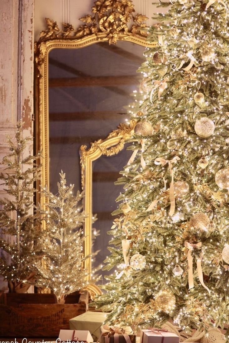 a decorated christmas tree sitting in front of a mirror with presents under it and gold trimmings