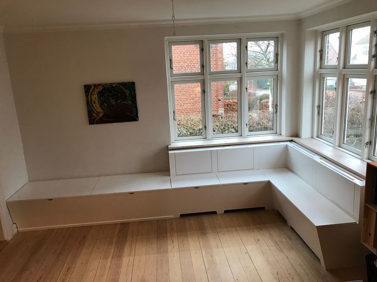 an empty room with wooden flooring and white painted walls, along with large windows