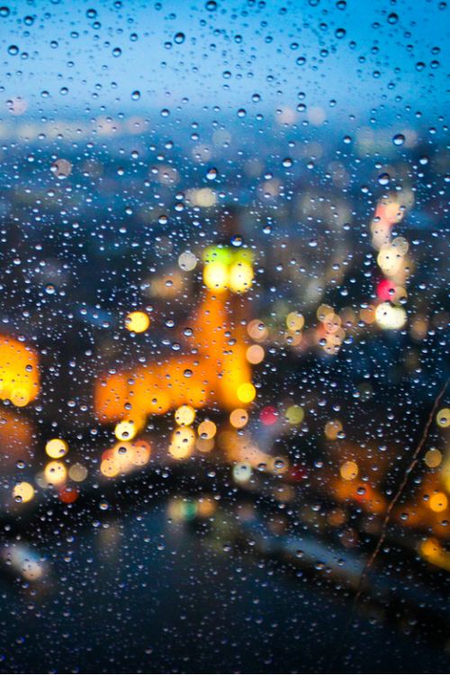 rain drops on a window with city lights in the background