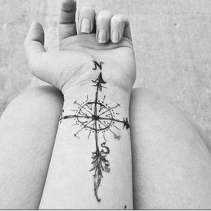 a black and white photo of a person's arm with a compass tattoo on it