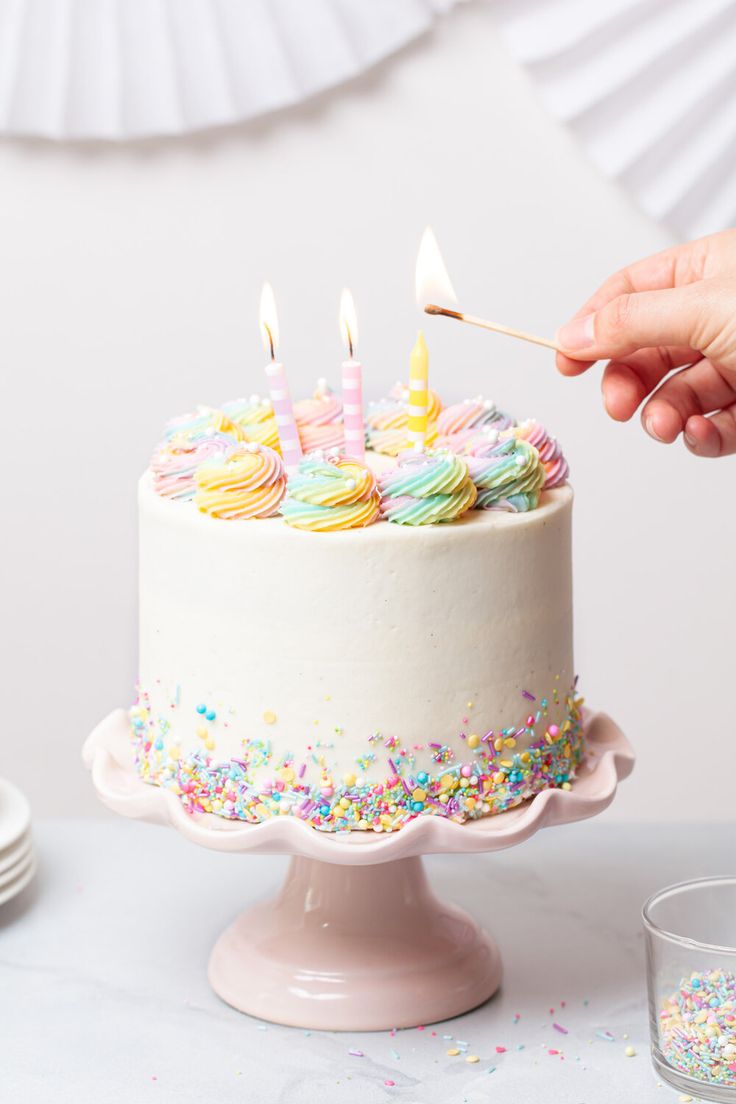 someone lighting candles on a birthday cake with sprinkles