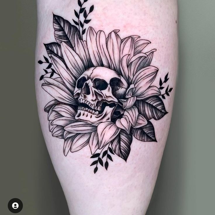 a skull and sunflower tattoo on the right thigh, with leaves in the background