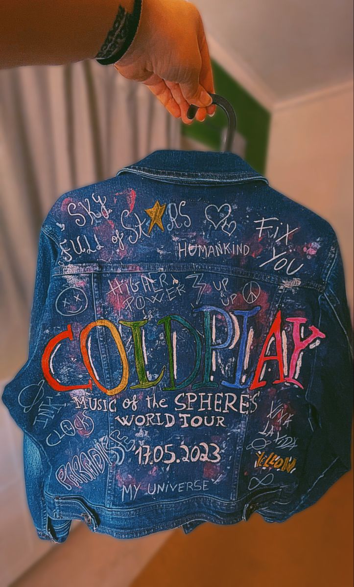 someone holding up a jean jacket with writing on it