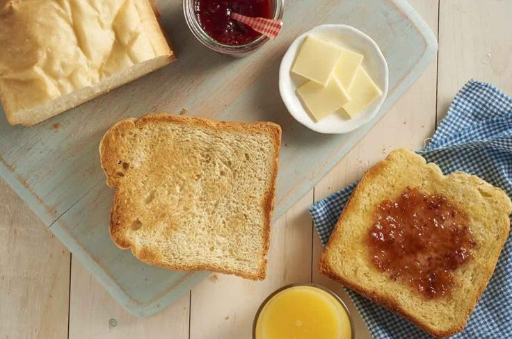 bread, butter and jam are on a cutting board