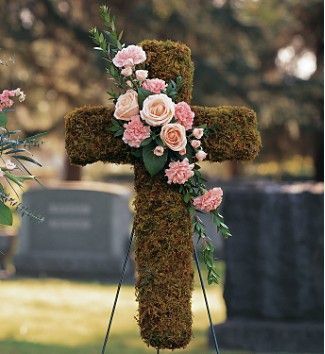 a cross made out of moss with pink flowers