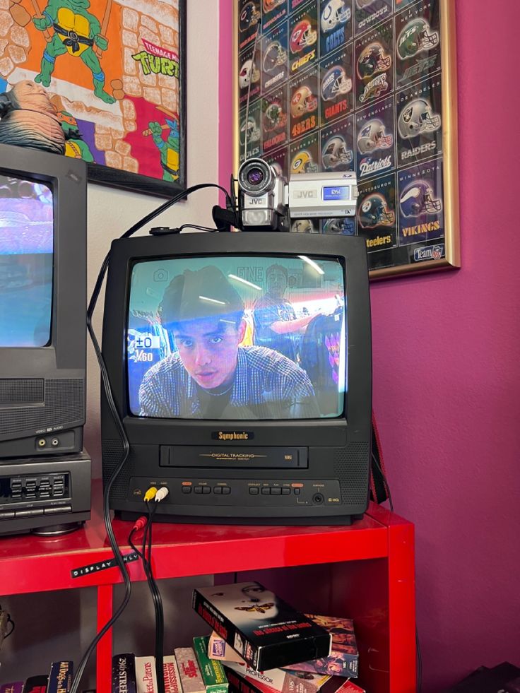 two televisions sitting on top of a red table