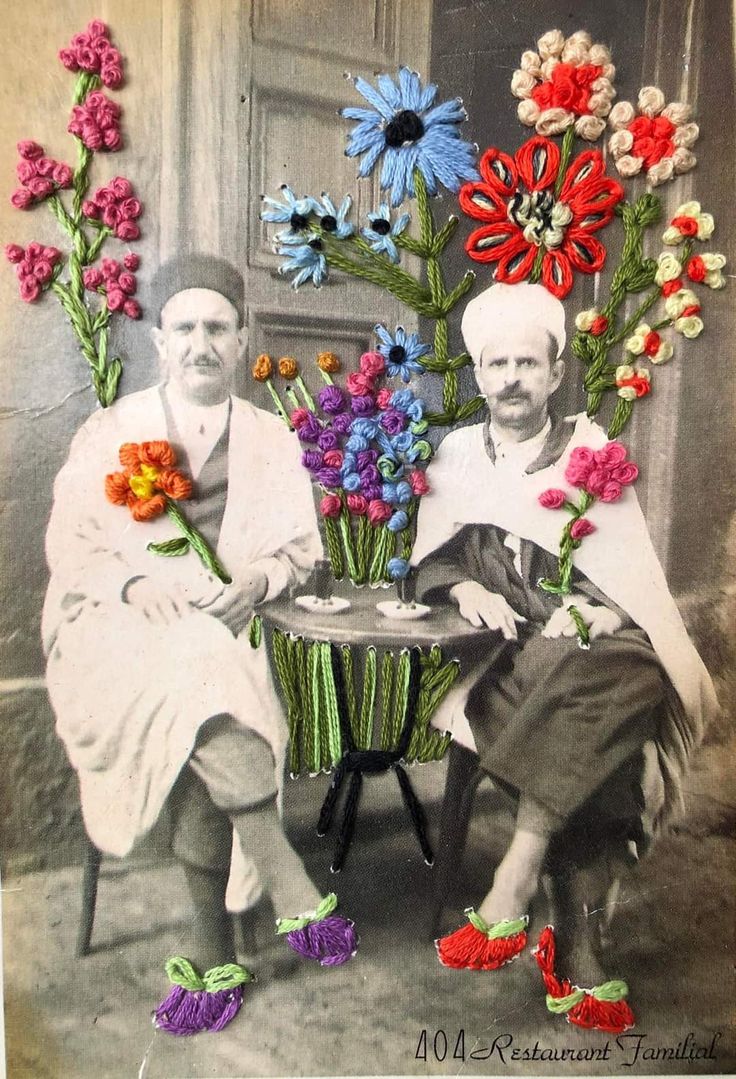 two men sitting next to each other with flowers in front of them on a table