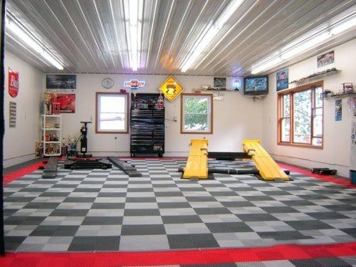 a garage with black and white checkered flooring, yellow ramps and windows