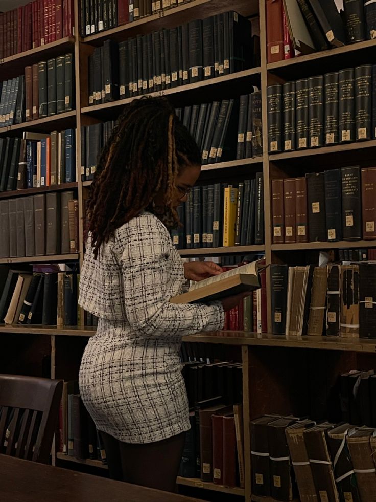 a woman standing in front of a book shelf filled with books