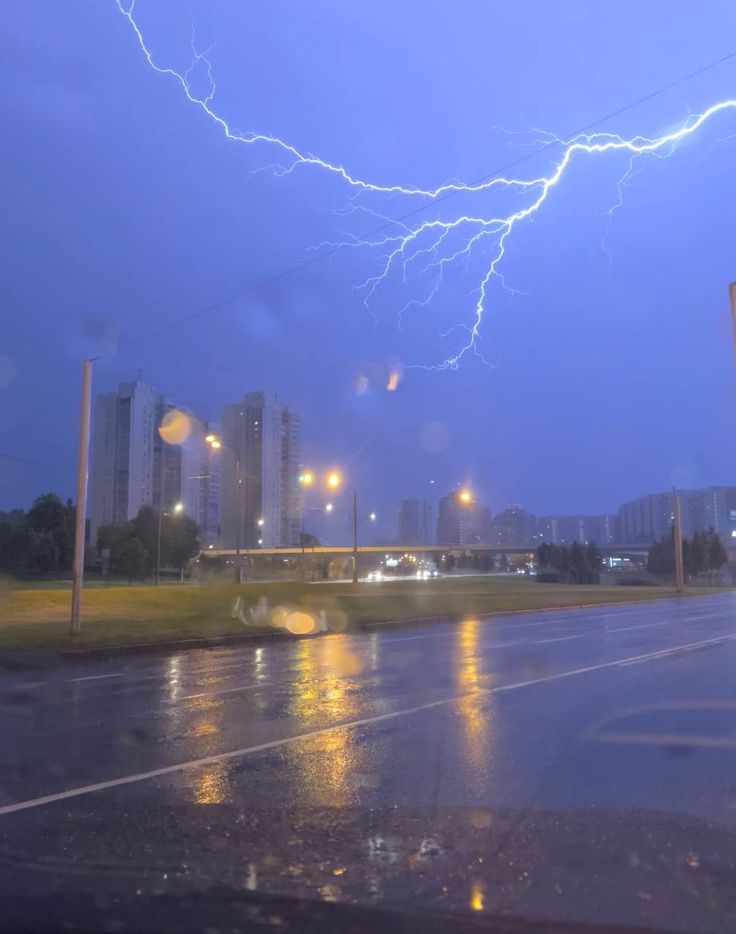 a lightning bolt is seen in the sky over a city street