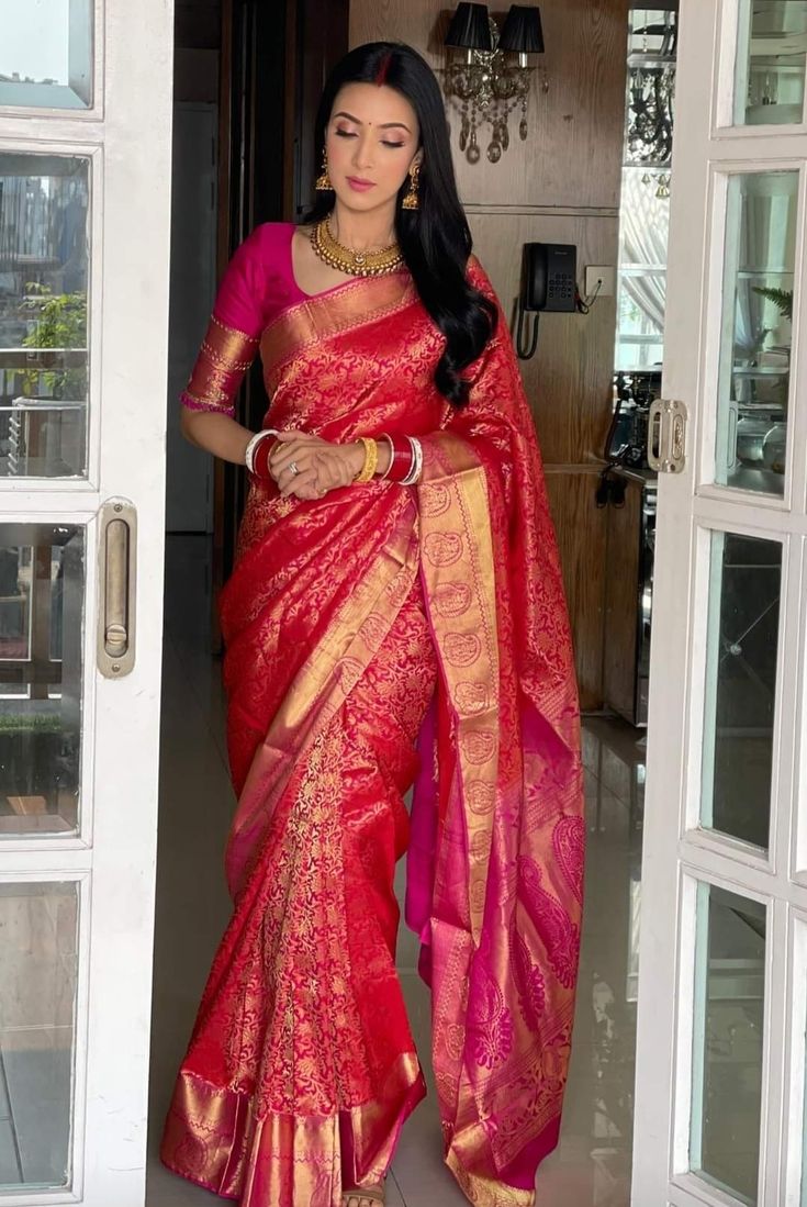 a woman in a red and gold sari is standing at the entrance to her home