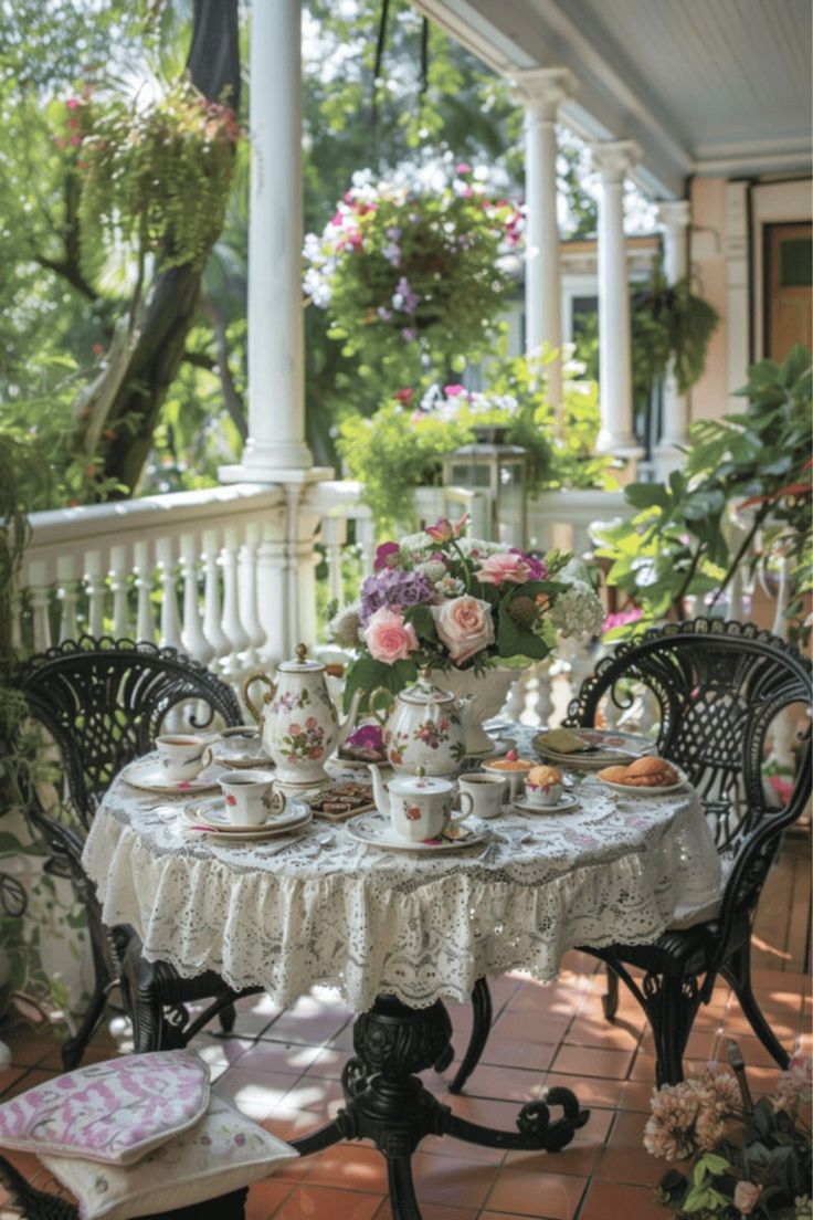 a table with tea cups and plates on it in the middle of a porch area