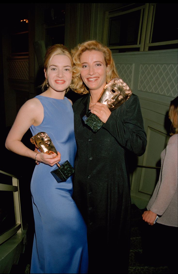 two women standing next to each other holding awards