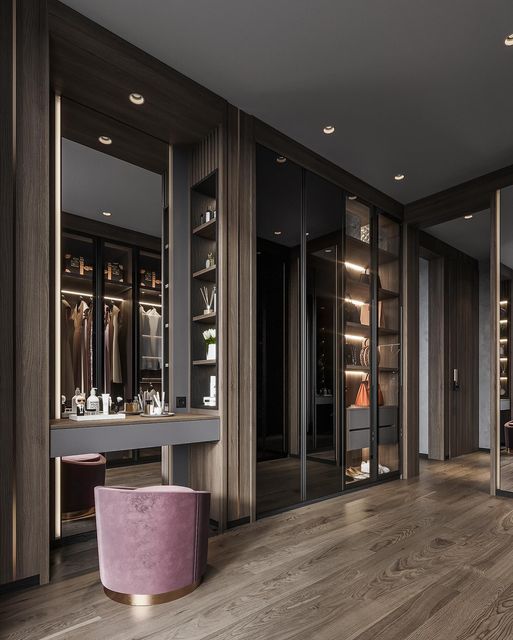 a large walk - in closet with mirrored doors and pink stools next to it