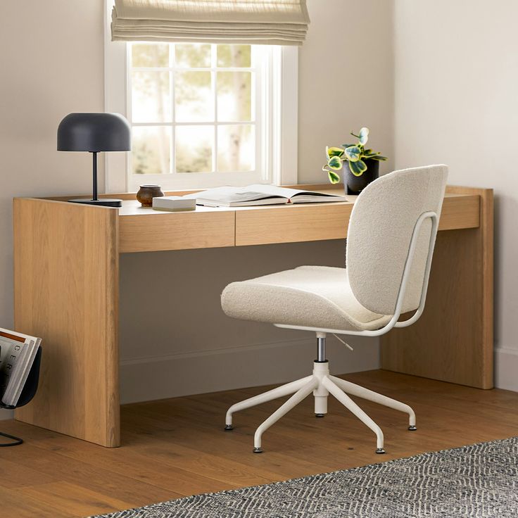 a white chair sitting in front of a desk with a lamp on top of it