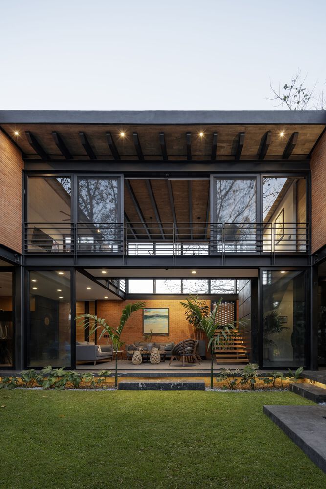 a modern house with glass walls and lots of windows on the outside, surrounded by grass