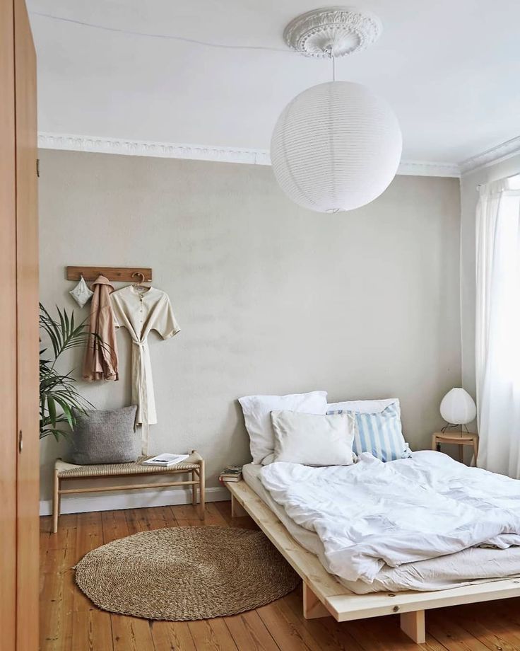 a bedroom with a bed, rug and hanging light fixture in the middle of the room