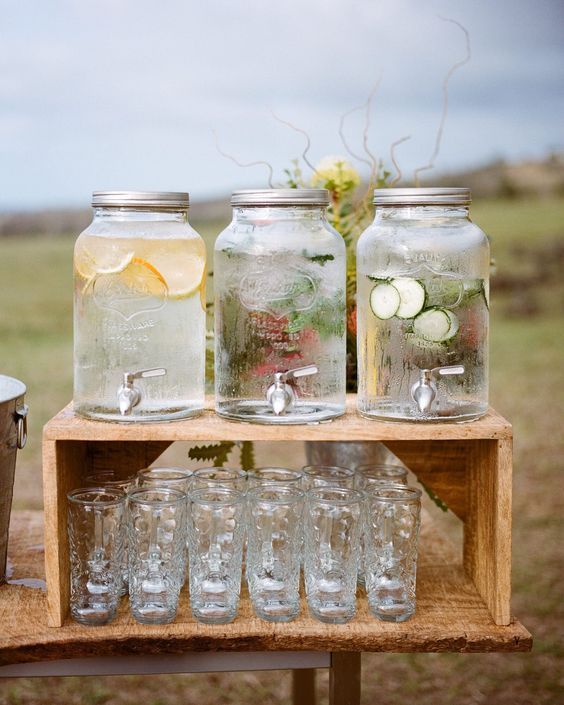 mason jars filled with water, lemons and cucumbers on a wooden table