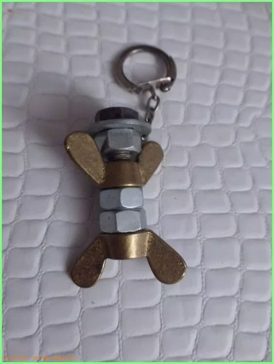 a keychain shaped like a teddy bear sitting on top of a white bed