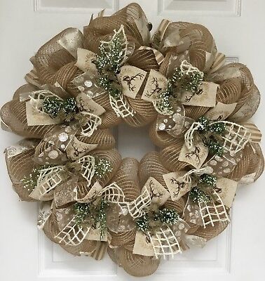 a wreath with burlocks and bows hanging on a door handle, in front of a white door