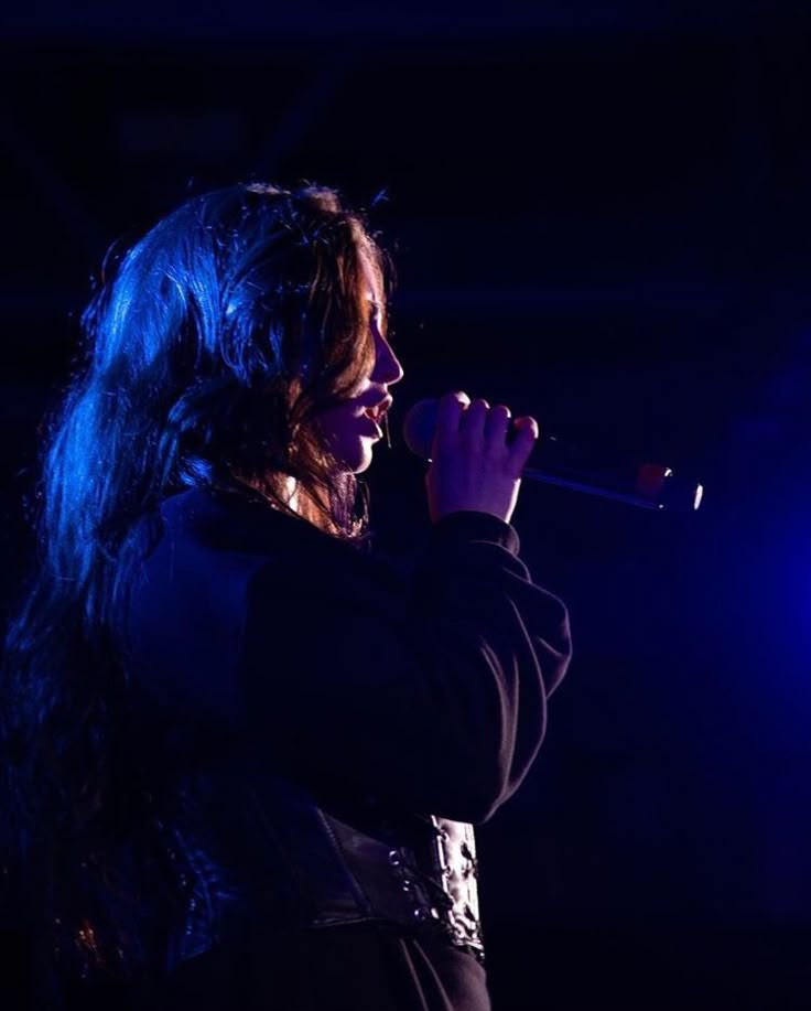 a woman with long hair singing into a microphone