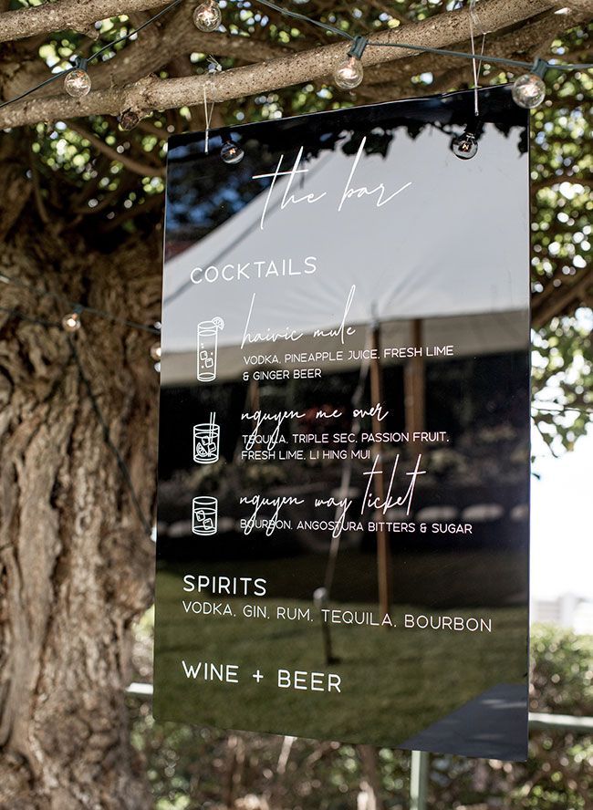 a sign hanging from the side of a tree in front of a large white tent