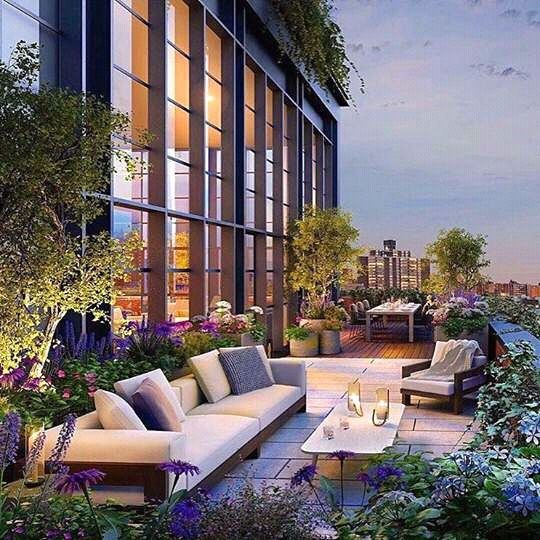 an outdoor living area with couches, tables and plants on the roof terrace at night