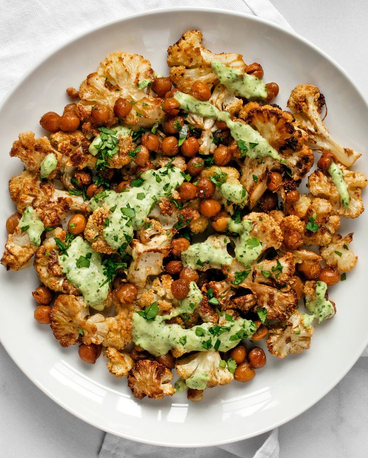 a white plate topped with cauliflower, chickpeas and avocado