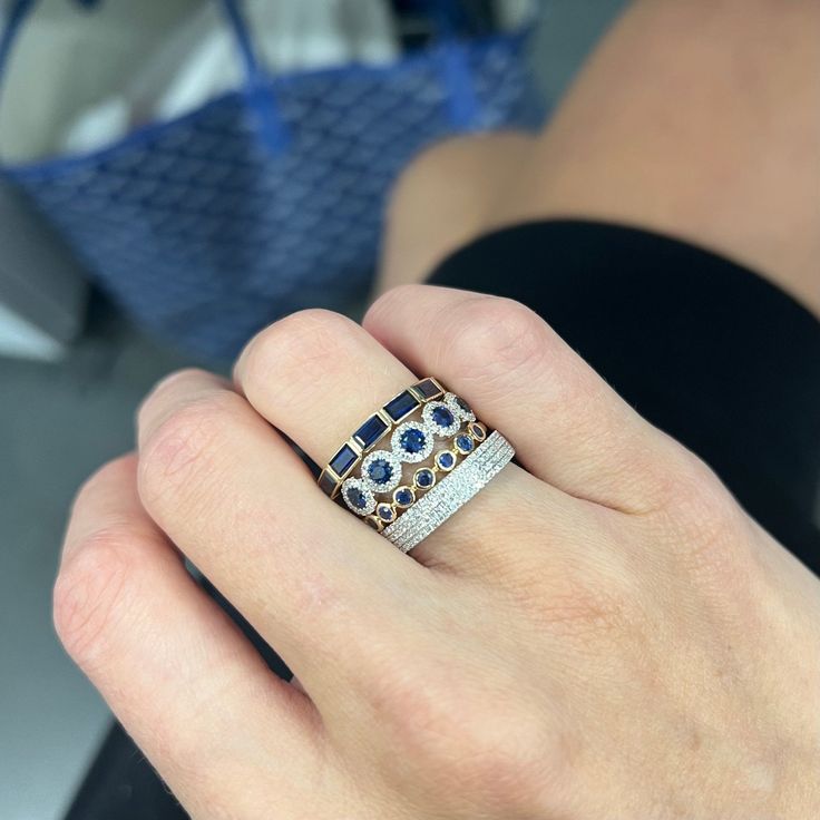 a woman's hand holding a ring with blue and white stones on it,