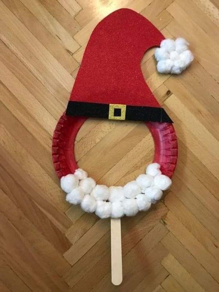 a paper plate santa hat with cotton balls on it and a toothpick in the middle