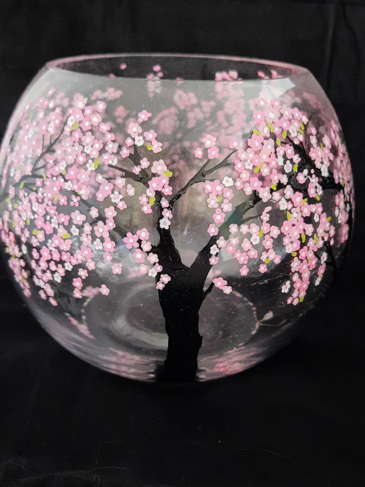 a glass bowl with pink flowers painted on the outside and inside, in front of a black background