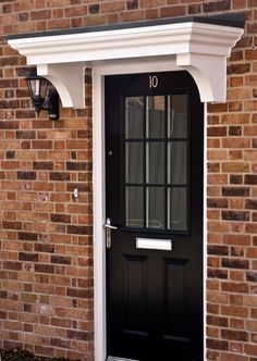 a black front door on a brick building with white trim around the top and bottom